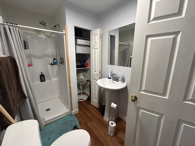 bathroom featuring walk in shower, toilet, and hardwood / wood-style floors