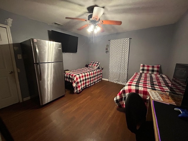 bedroom with dark hardwood / wood-style floors, a textured ceiling, stainless steel fridge, and ceiling fan