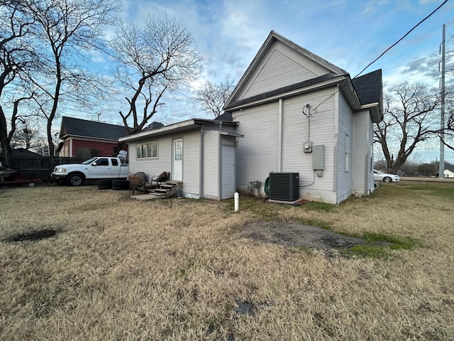 back of house featuring central AC unit and a lawn