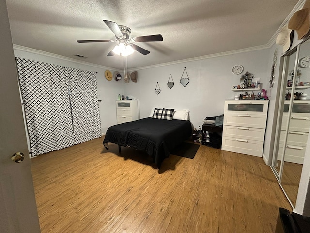 bedroom with crown molding, ceiling fan, a textured ceiling, and light wood-type flooring