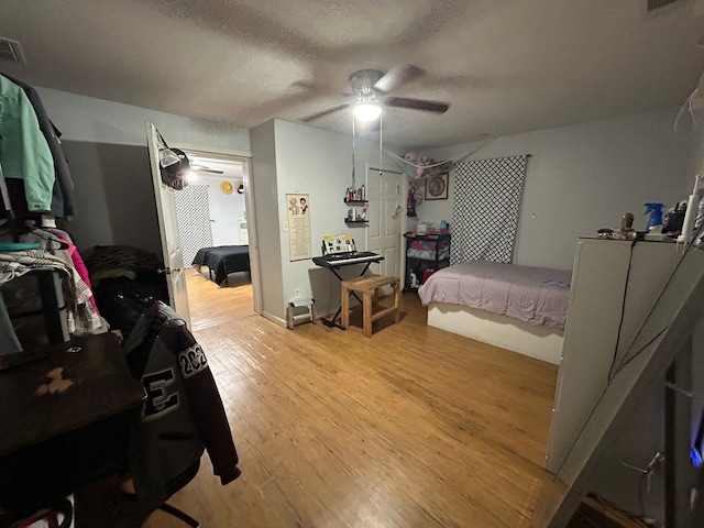 bedroom with ceiling fan, a textured ceiling, and light wood-type flooring