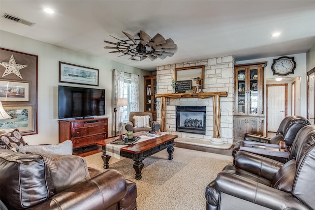 living room featuring hardwood / wood-style flooring, a stone fireplace, and ceiling fan