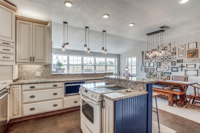 kitchen with a breakfast bar, appliances with stainless steel finishes, a kitchen island, decorative light fixtures, and cream cabinetry