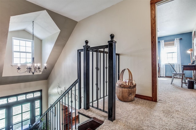 staircase featuring an inviting chandelier, vaulted ceiling, and carpet