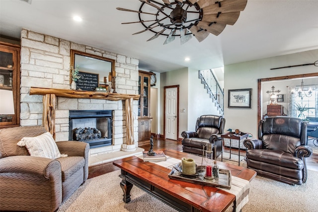 living room featuring wood-type flooring, a fireplace, and ceiling fan with notable chandelier