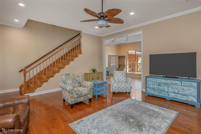 living room featuring hardwood / wood-style flooring, ceiling fan, and crown molding