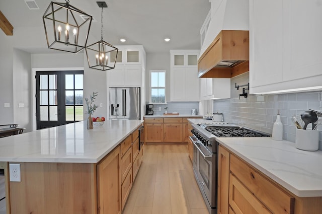 kitchen with tasteful backsplash, custom range hood, visible vents, stainless steel appliances, and a chandelier