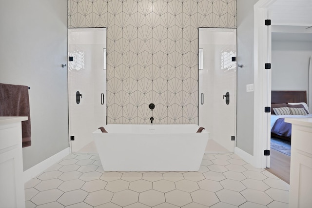 ensuite bathroom with baseboards, ensuite bathroom, a freestanding tub, and a stall shower
