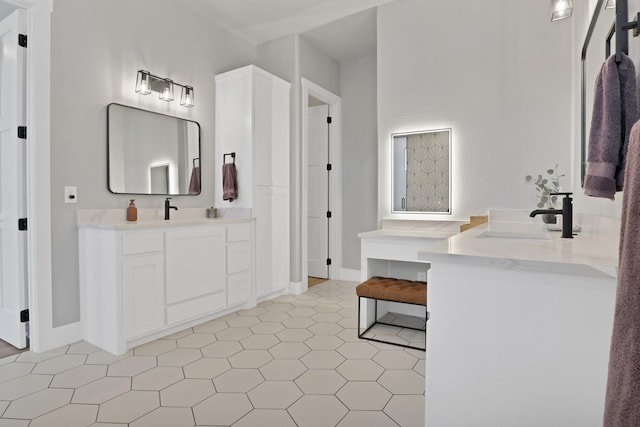 bathroom with two vanities, baseboards, and a sink