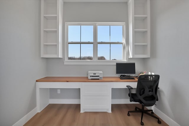 office featuring baseboards, light wood-style floors, and built in study area