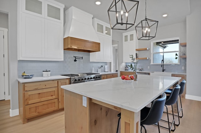 kitchen featuring open shelves, a sink, premium range hood, a center island, and range