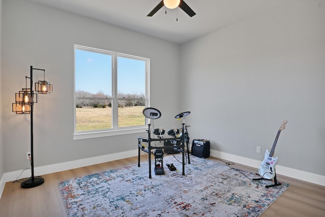 workout area featuring baseboards, wood finished floors, and ceiling fan