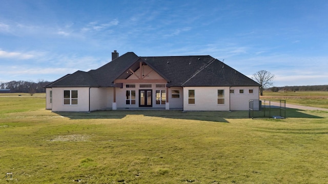 rear view of property featuring a yard, a shingled roof, french doors, and a chimney