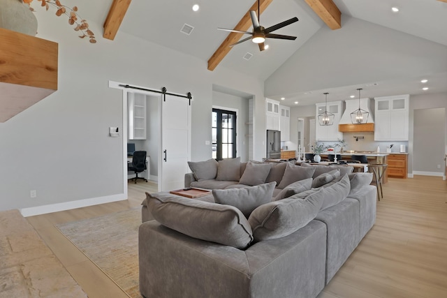 living room with ceiling fan, beam ceiling, high vaulted ceiling, a barn door, and light wood-type flooring