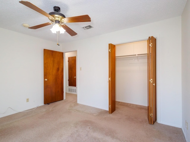 unfurnished bedroom with light carpet, a textured ceiling, and a closet