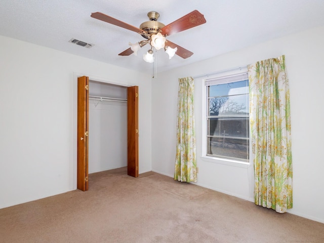 unfurnished bedroom featuring ceiling fan, a closet, and light carpet