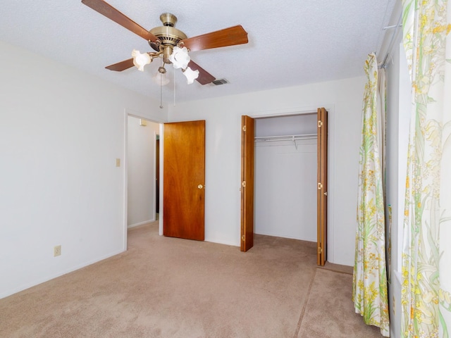 unfurnished bedroom with ceiling fan, light colored carpet, a textured ceiling, and a closet