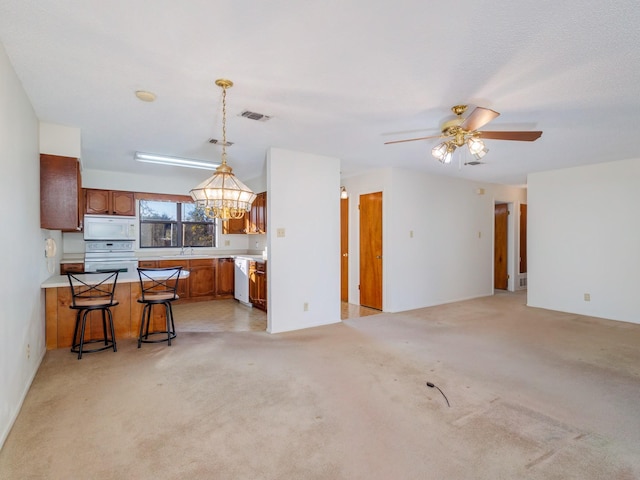 kitchen with pendant lighting, a kitchen bar, light colored carpet, kitchen peninsula, and white appliances