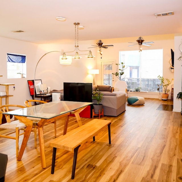 living area with ceiling fan, visible vents, and wood finished floors