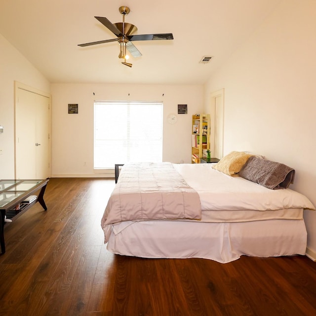 bedroom with lofted ceiling, wood finished floors, visible vents, baseboards, and a ceiling fan