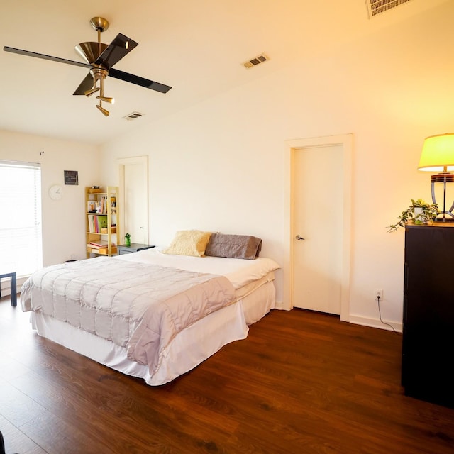 bedroom with dark wood-type flooring, lofted ceiling, and visible vents