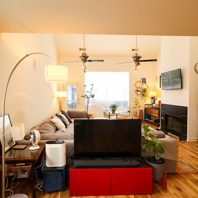 living room with wood finished floors, visible vents, a fireplace, and ceiling fan