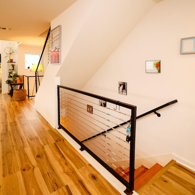 staircase with visible vents, vaulted ceiling, and wood finished floors