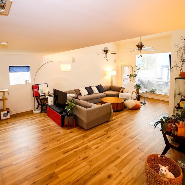 living room with light wood-type flooring, visible vents, and ceiling fan