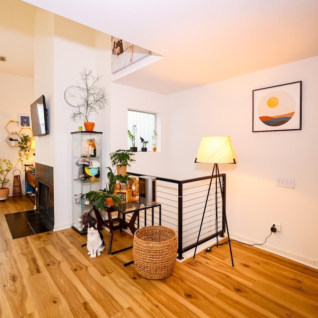 sitting room featuring a tile fireplace, visible vents, an upstairs landing, and wood finished floors