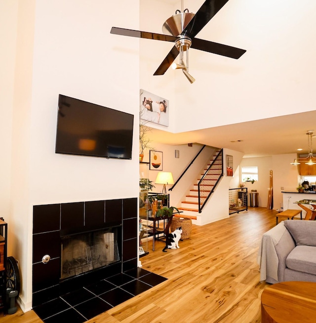 living area with ceiling fan, stairway, a fireplace, and wood finished floors