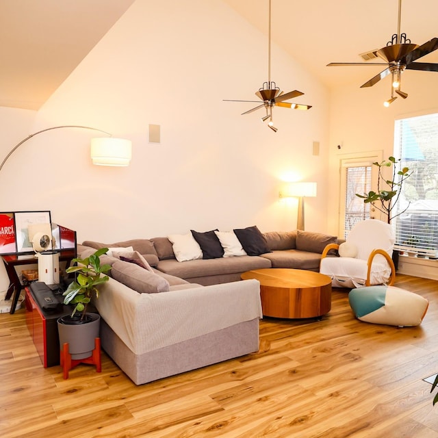 living room with light wood-type flooring, high vaulted ceiling, and a ceiling fan