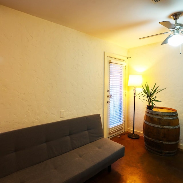 sitting room with ceiling fan, a textured wall, and carpet flooring