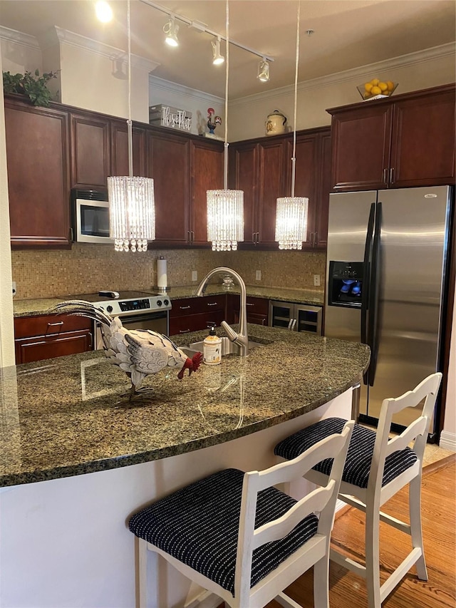 kitchen with stainless steel appliances, sink, a breakfast bar area, and dark stone counters