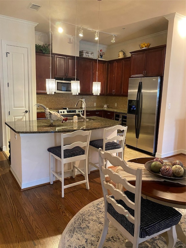 kitchen featuring stainless steel appliances, hanging light fixtures, dark wood-type flooring, and decorative backsplash