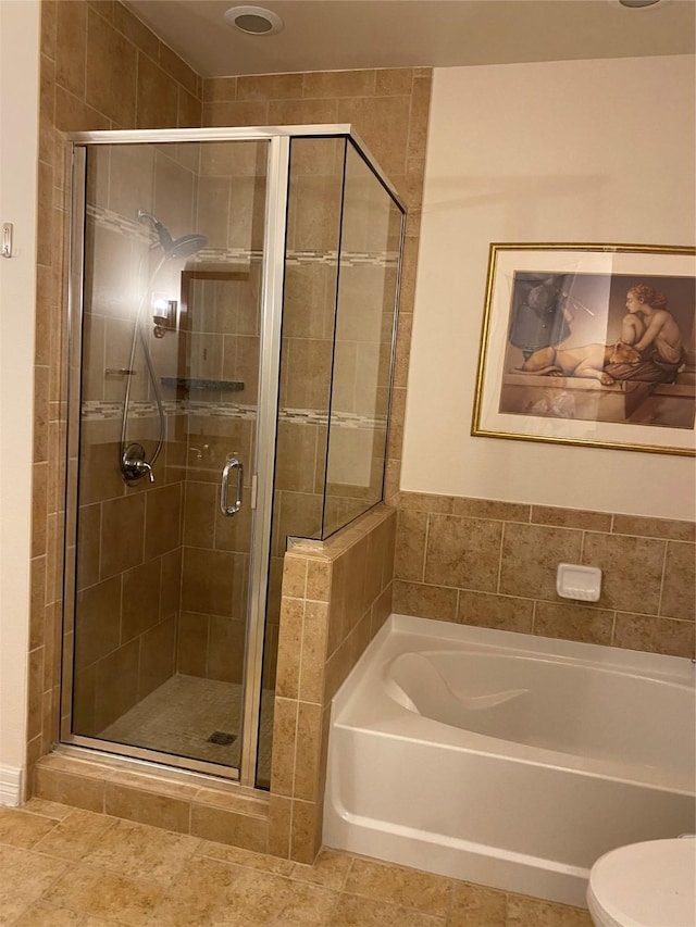 bathroom featuring tile patterned floors, toilet, and separate shower and tub