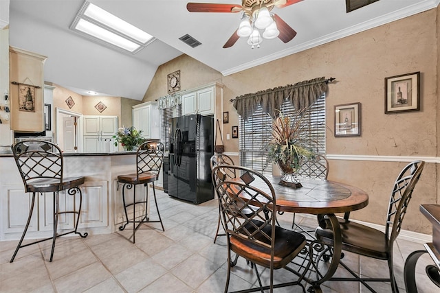 dining space with light tile patterned floors, vaulted ceiling, ornamental molding, and ceiling fan