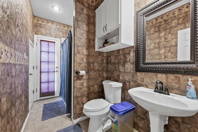 bathroom with tile walls, sink, and toilet