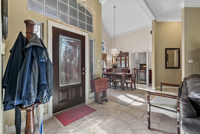 entryway featuring an inviting chandelier, light tile patterned floors, crown molding, and high vaulted ceiling