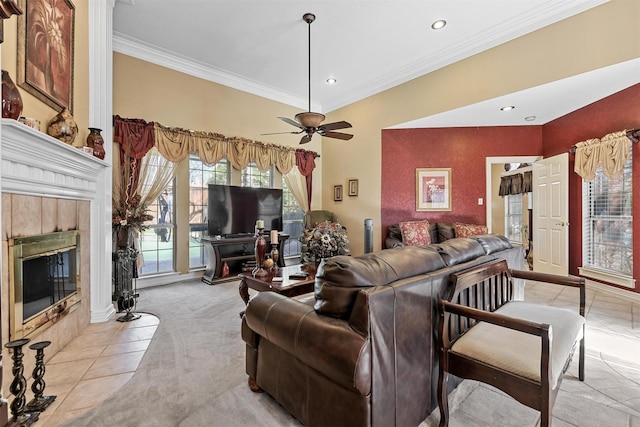 carpeted living room featuring a tiled fireplace, crown molding, and ceiling fan