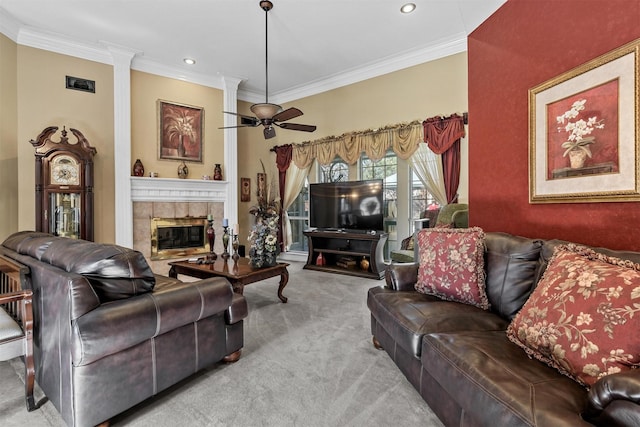 living room with ceiling fan, light colored carpet, ornamental molding, and a tile fireplace