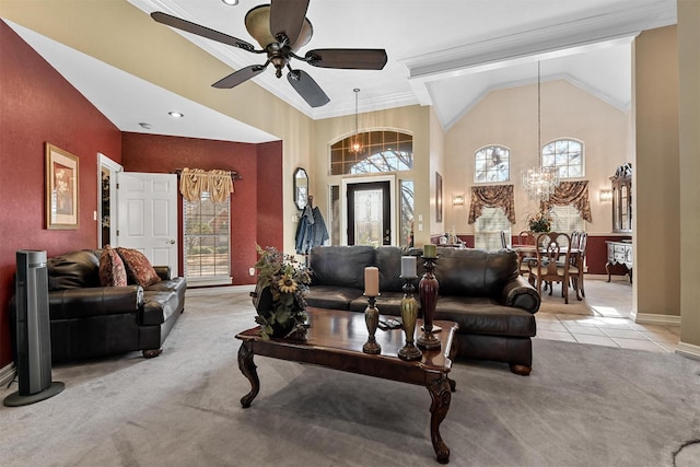 carpeted living room with crown molding, ceiling fan with notable chandelier, and high vaulted ceiling