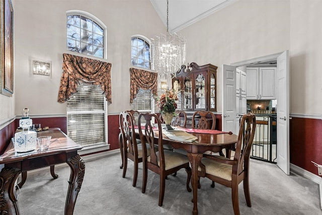 dining area featuring crown molding, a chandelier, light carpet, and high vaulted ceiling