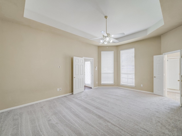 carpeted spare room featuring a raised ceiling and ceiling fan