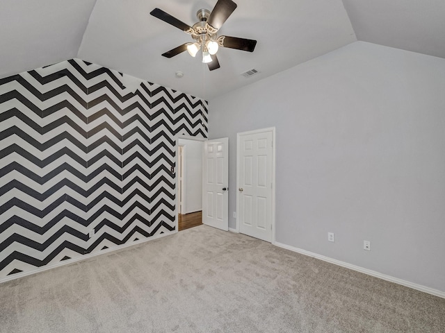 spare room with vaulted ceiling, light colored carpet, and ceiling fan