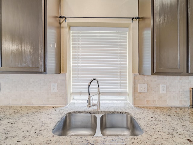 kitchen featuring light stone counters, sink, and decorative backsplash