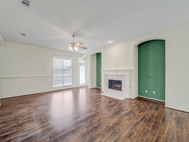 unfurnished living room with a tile fireplace, ceiling fan, and dark hardwood / wood-style flooring