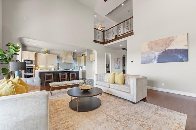 living room featuring ceiling fan, wood-type flooring, and a high ceiling