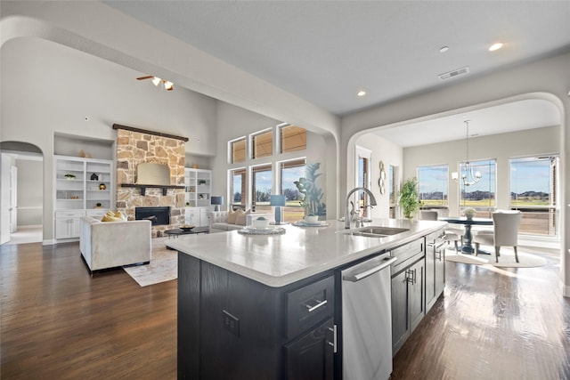 kitchen featuring pendant lighting, sink, dishwasher, a kitchen island with sink, and a fireplace