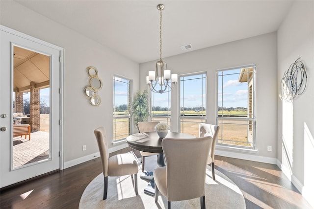 dining room featuring a notable chandelier, a wealth of natural light, and dark hardwood / wood-style floors