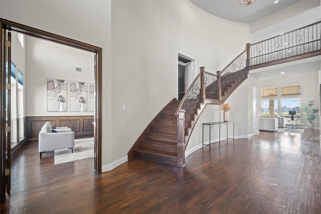 stairway with hardwood / wood-style flooring and a towering ceiling